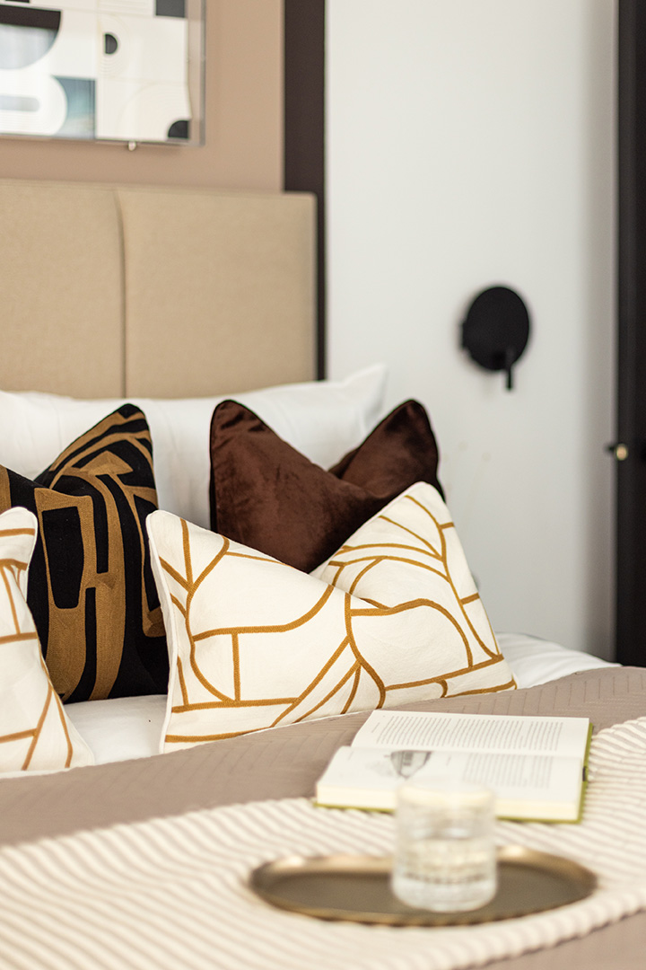 Cozy bed with patterned pillows, a book, and a drink-15