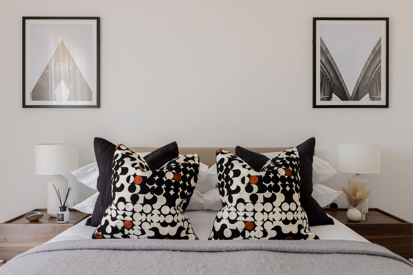 Modern bedroom with framed prints, patterned pillows, and lamps-36