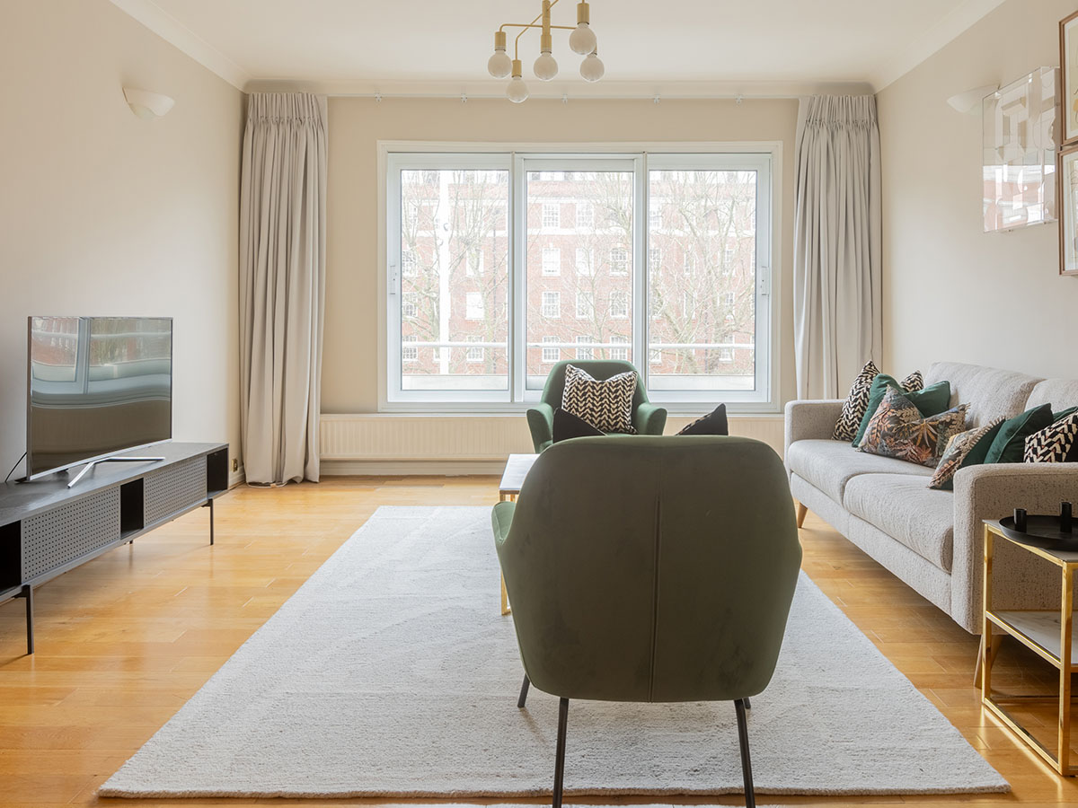 Styled apartment lounge with green chairs and modern sofa